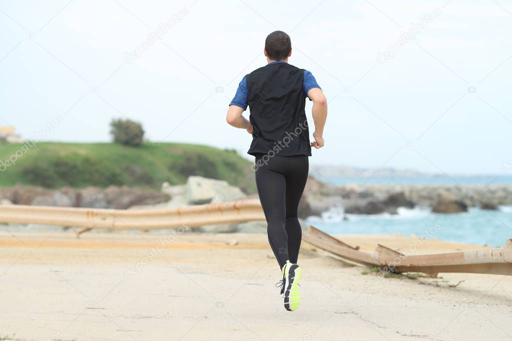 Back view of a runner running alone on the beach
