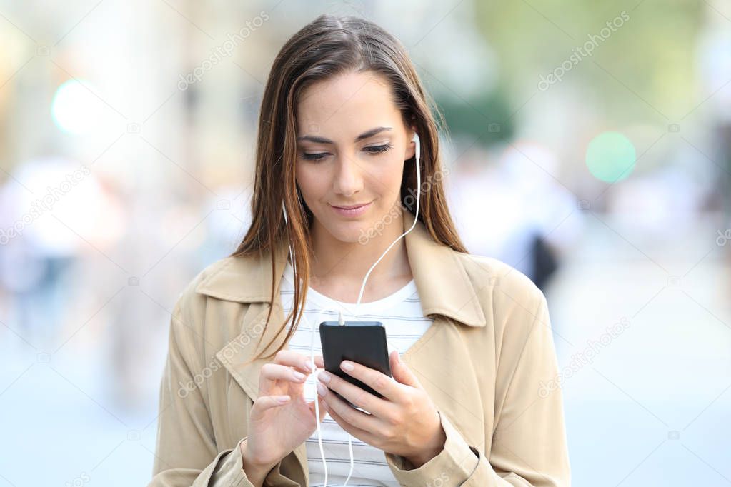 Front view of serious girl listening to music on phone
