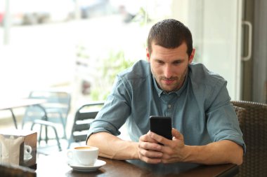 Bir kafede akıllı telefon kullanan yetişkin adam