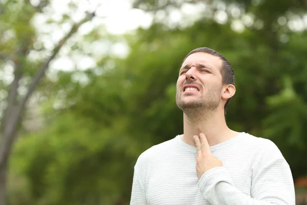 Homem sofrendo dor de garganta reclamando em um parque — Fotografia de Stock