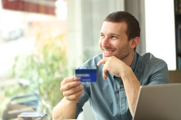 Feliz comprador adulto pensando en tener una tarjeta de crédito en un bar — Foto de Stock
