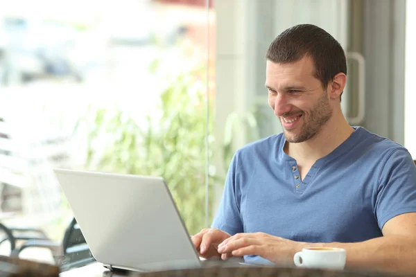 Happy adult man using a laptop in a bar — Stock Photo, Image