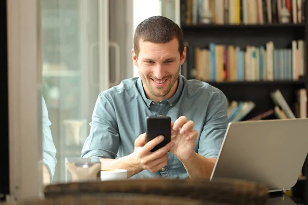 Ευτυχισμένος άνθρωπος χρησιμοποιώντας το τηλέφωνο και το φορητό υπολογιστή σε μια καφετέρια — Φωτογραφία Αρχείου