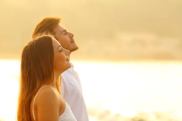 Avslappnad par på stranden andas frisk luft vid solnedgången — Stockfoto