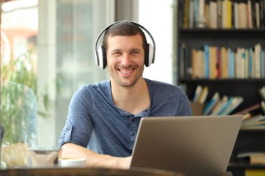 Barda kulaklık ve dizüstü bilgisayarla poz veren mutlu adam.