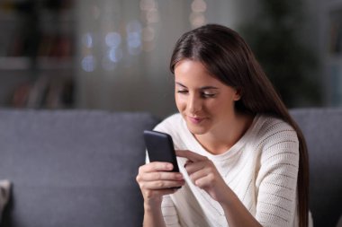 Ciddi kız gece evde cep telefonu kullanıyor.