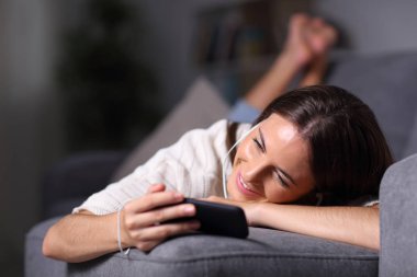 Mutlu kız akıllı telefondan video izleyip dinliyor.