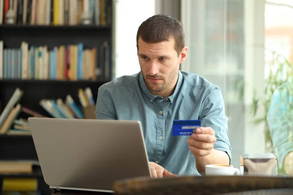 Serious buyer buys with credit card and laptop in a bar — Stock Photo, Image