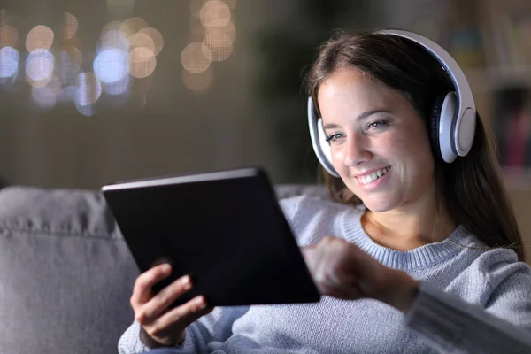 Happy woman wearing headphones uses a tablet — Stok Foto