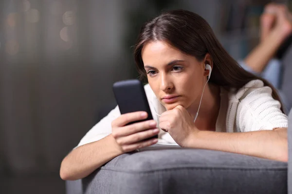 Chica seria escuchando música leyendo contenido del teléfono — Foto de Stock