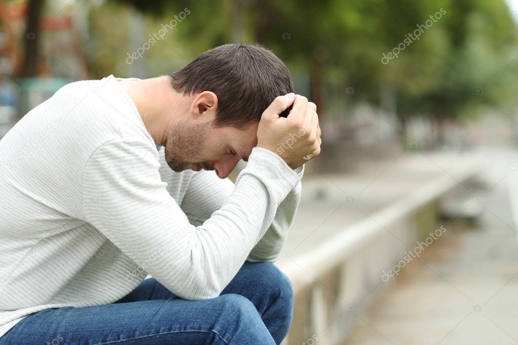 Sad adult man complaining alone in a park