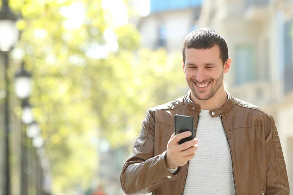 Hombre adulto feliz usando un teléfono inteligente en la calle — Foto de Stock