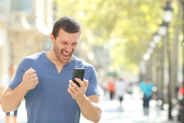Возбужденный человек проверяет хорошие новости на мобильном телефоне — стоковое фото