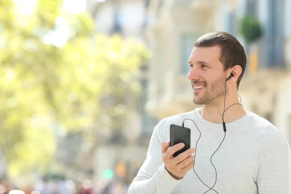 Hombre adulto feliz escuchando música mirando al lado en la calle —  Fotos de Stock