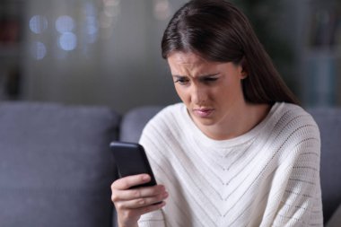Endişeli kız gece akıllı telefon haberlerini kontrol ediyor.