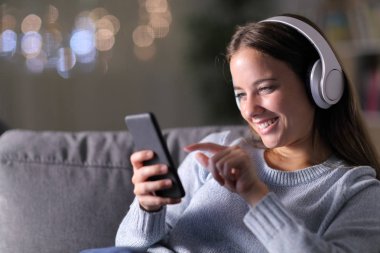 Kulaklık ve akıllı telefonla müzik dinleyen mutlu bir kadın.