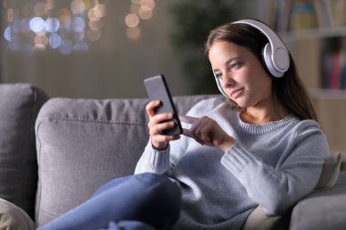 Kadın kulaklık ve telefon kullanarak müzik dinliyor.