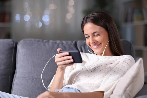 Chica feliz viendo los medios de comunicación en el teléfono inteligente en la noche — Foto de Stock