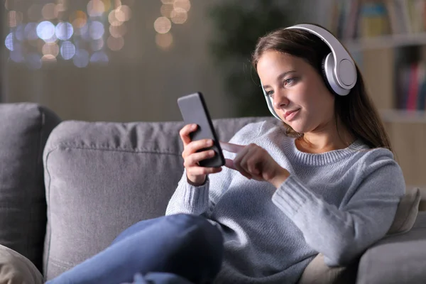 Mujer escuchando música usando auriculares y teléfono — Foto de Stock