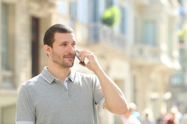 Ciddi bir yetişkin adam sokakta telefonla konuşuyor.