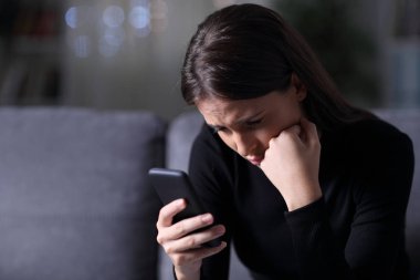 Endişeli kız gece yarısı telefon mesajı okuyor.