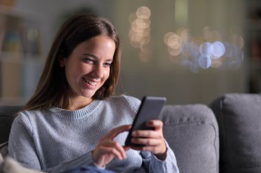 Mutlu kadın evde cep telefonu içeriğini kontrol ediyor