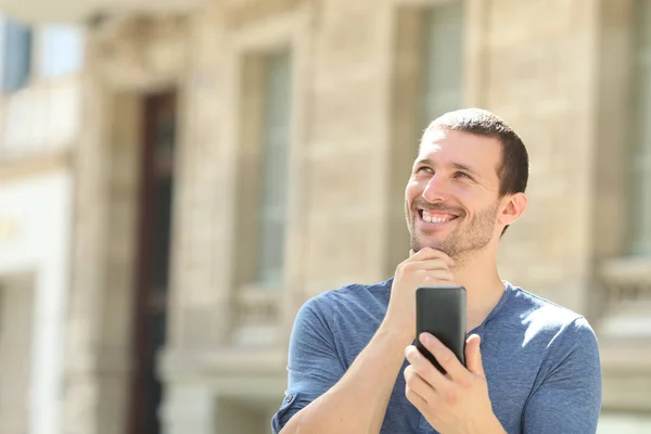 Nachdenklicher Mann mit Handy schaut auf der Straße zur Seite — Stockfoto