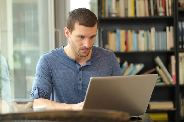 Uomo serio che utilizza un computer portatile in una caffetteria o in casa — Foto Stock