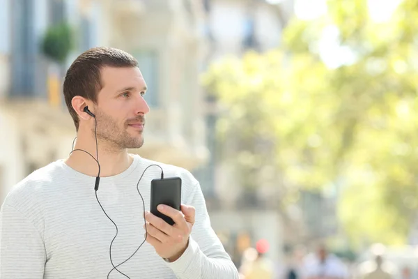 Volwassen man kijkt naar kant luisteren naar muziek in de straat — Stockfoto