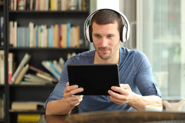 Serieuze man met tablet en koptelefoon in een coffeeshop — Stockfoto