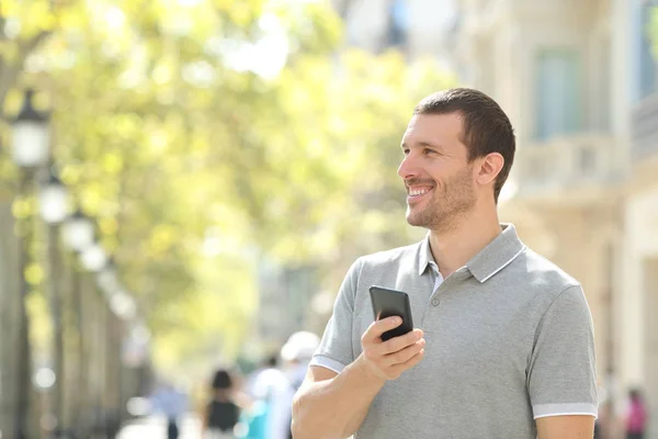 Uomo felice guarda lato tenendo smart phone in strada — Foto Stock