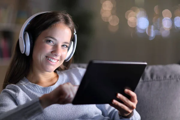 Menina feliz usando fones de ouvido mantém tablet olhando para você — Fotografia de Stock