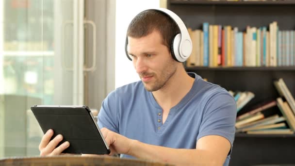 Hombre Serio Usando Auriculares Usando Una Tableta Una Cafetería — Vídeos de Stock