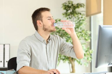 Ofis çalışanı çalışıyor ve şişe su içiyor.