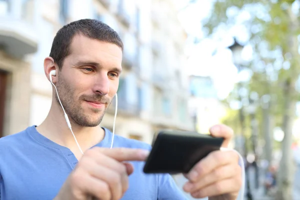 Hombre adulto con auriculares en busca de vídeo en el teléfono —  Fotos de Stock