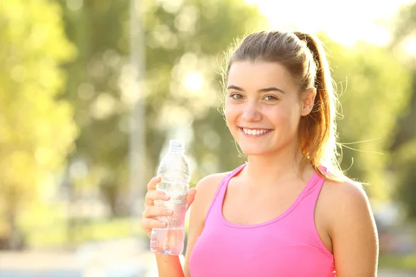 Šťastný běžec se podívá na kameru držící láhev s vodou — Stock fotografie