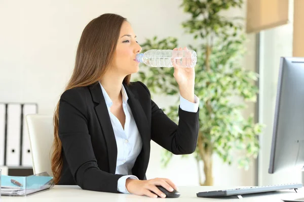 Affärskvinna dricker vatten på flaska på kontoret — Stockfoto