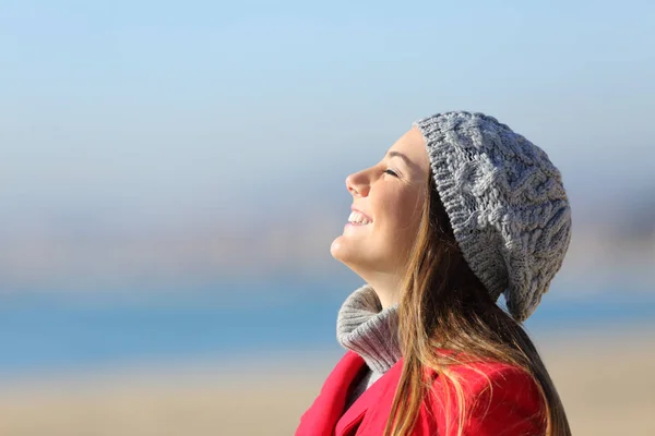 Счастливая женщина дышит глубоко свежим воздухом на пляже зимой — стоковое фото