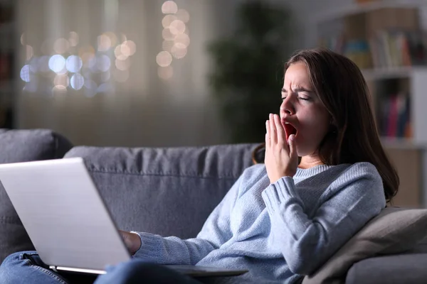 Mujer cansada usando el ordenador portátil bostezando en la noche —  Fotos de Stock