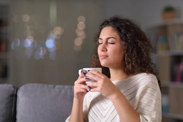Розслаблена жінка пахне чашкою кави вночі — стокове фото