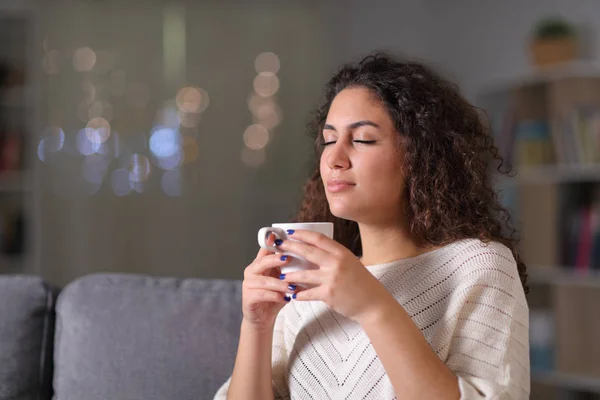 Mujer relajada oliendo taza de café en la noche — Foto de Stock