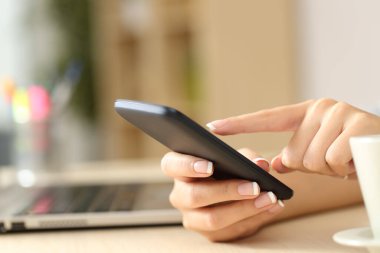 Evdeki bir masada oturan kadınların ellerini cep telefonuyla kapat.