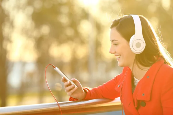 Lycklig Kvinna Med Hörlurar Lyssnar Musik Smarttelefon Balkong Vid Solnedgången — Stockfoto