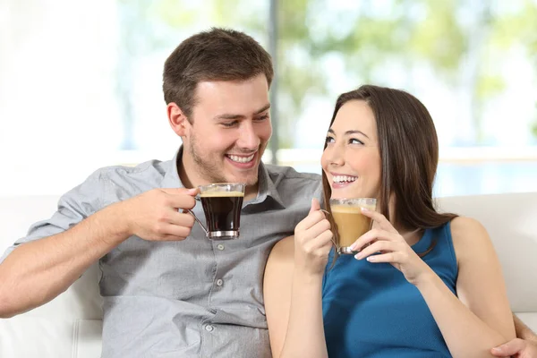 Casal Feliz Com Xícaras Café Olhando Para Outro Sentado Sofá — Fotografia de Stock