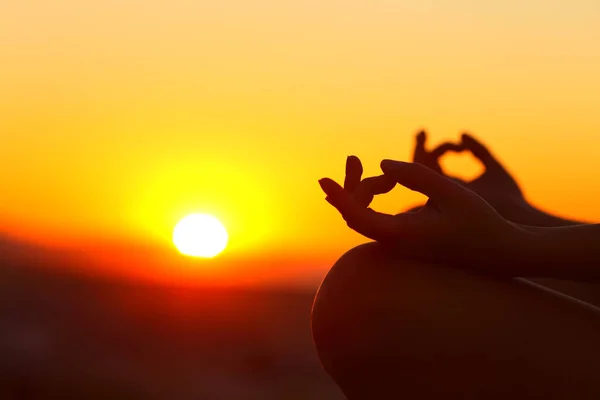 Close up of woman hands silhouette doing yoga relaxing at sunset outdoor