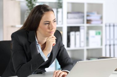 Ofisteki masasında laptopuyla oturan düşünceli yönetici kadın.