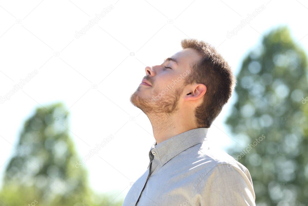 Side view of a man breathing fresh air standing outdoors on a green park