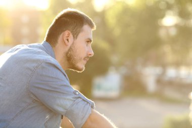 Düşünceli bir adam balkonda dikilip manzarayı seyrediyor.