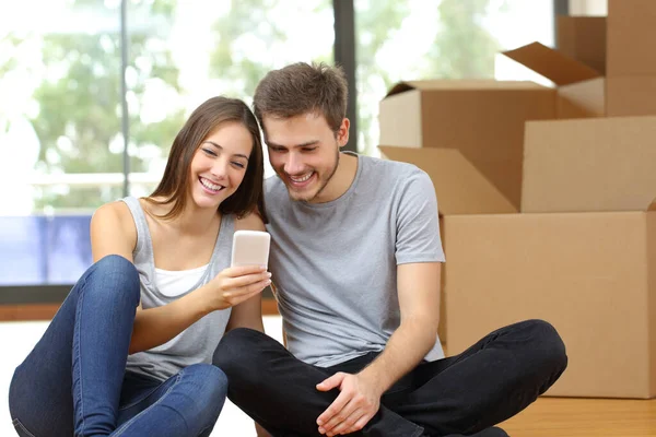 Casal Feliz Movendo Para Casa Verificando Telefone Inteligente Com Caixas — Fotografia de Stock