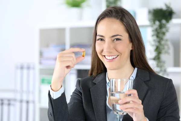 幸せな幹部の女性のフロントビューは オフィスでビタミンの錠剤と水のガラスを示しています — ストック写真